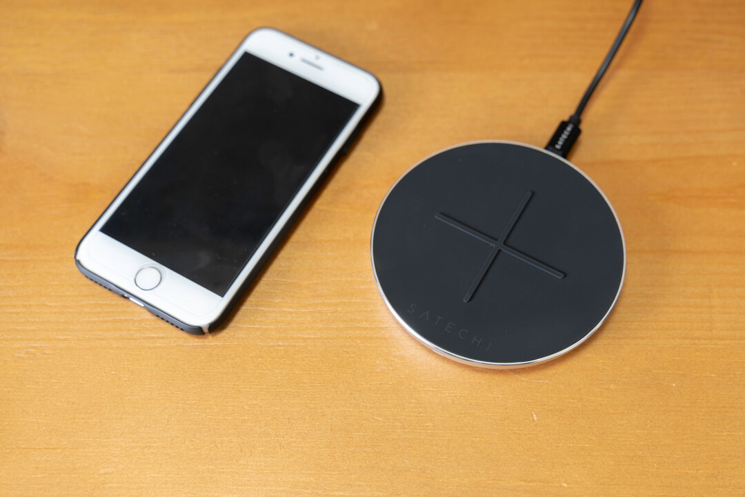 Satechiのワイヤレス充電パッドとiPhoneを並べて大きさを比較している様子
